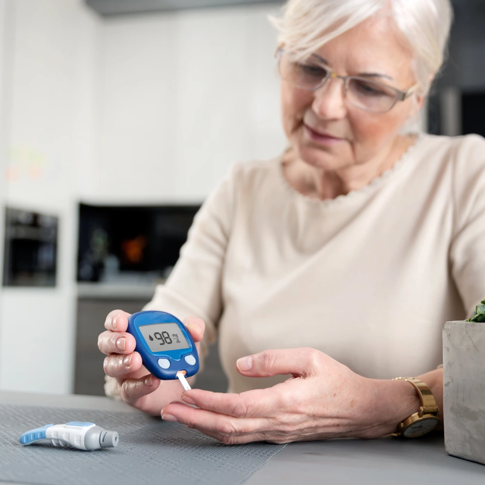 An elderly person using a blue glucose meter to check their blood sugar level.