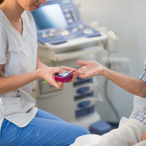 Nurse using a glucometer to check a patient's blood sugar level during a home visit